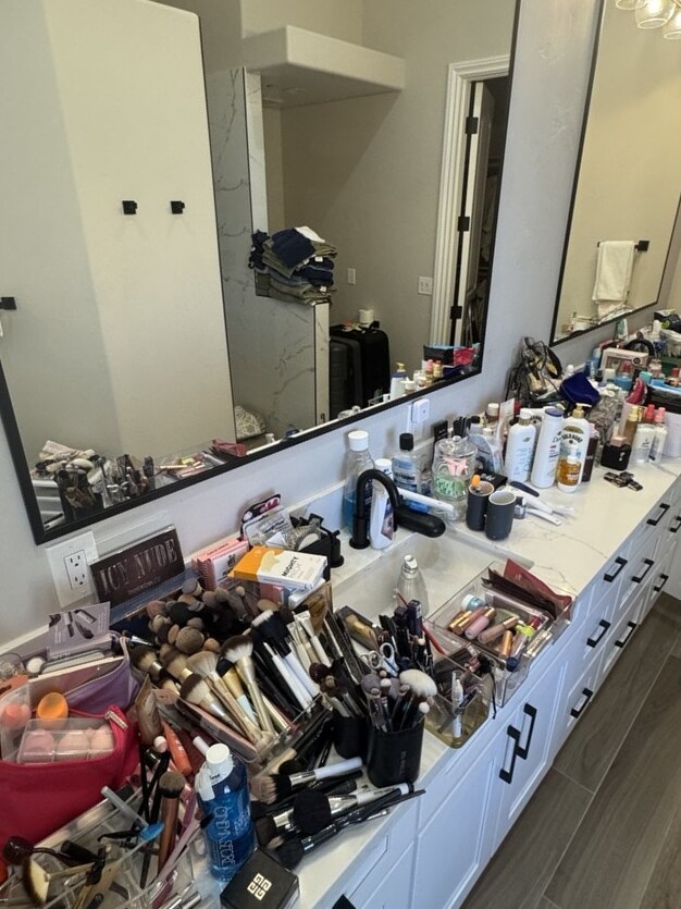 Primary bathroom vanity in a Las Vegas home before packing — makeup brushes, palettes and skincare bottles covering the full length of the quartz counter