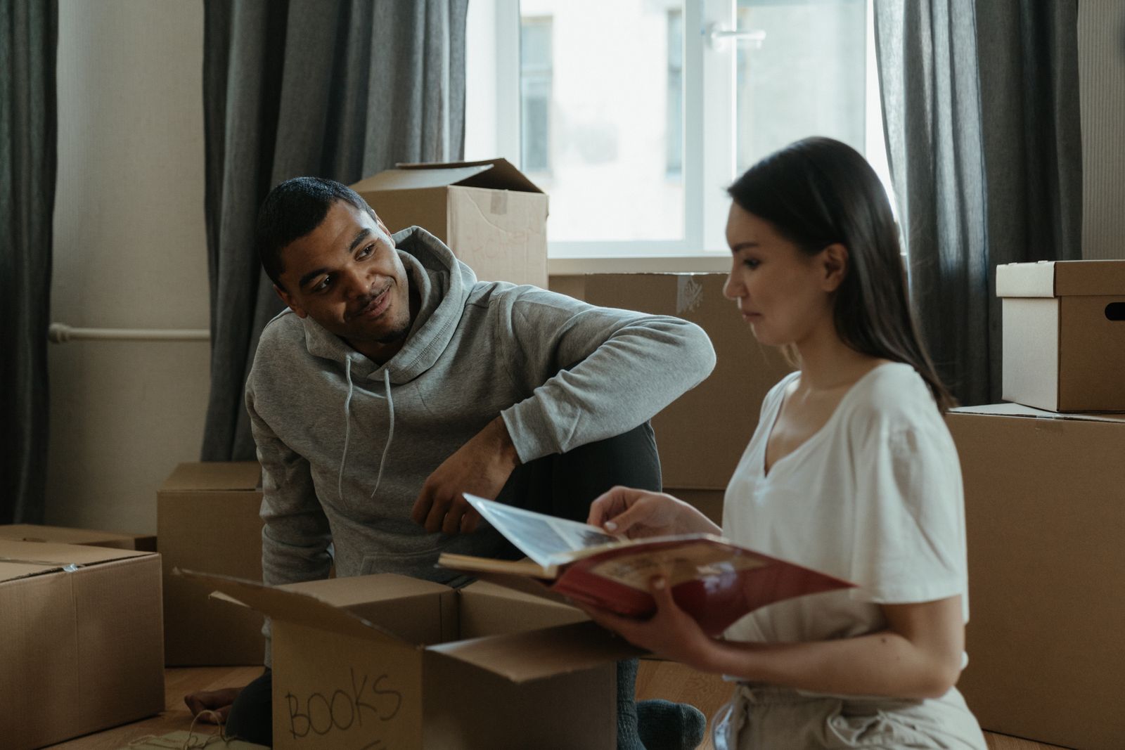 Couple unpacking moving boxes together in the living room of their new home