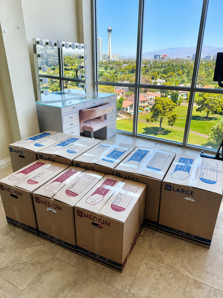 Labeled moving boxes stacked in a luxury Las Vegas high-rise with the Strip skyline visible through floor-to-ceiling windows — Lifelystyle professional packing service prepares your home for a seamless move