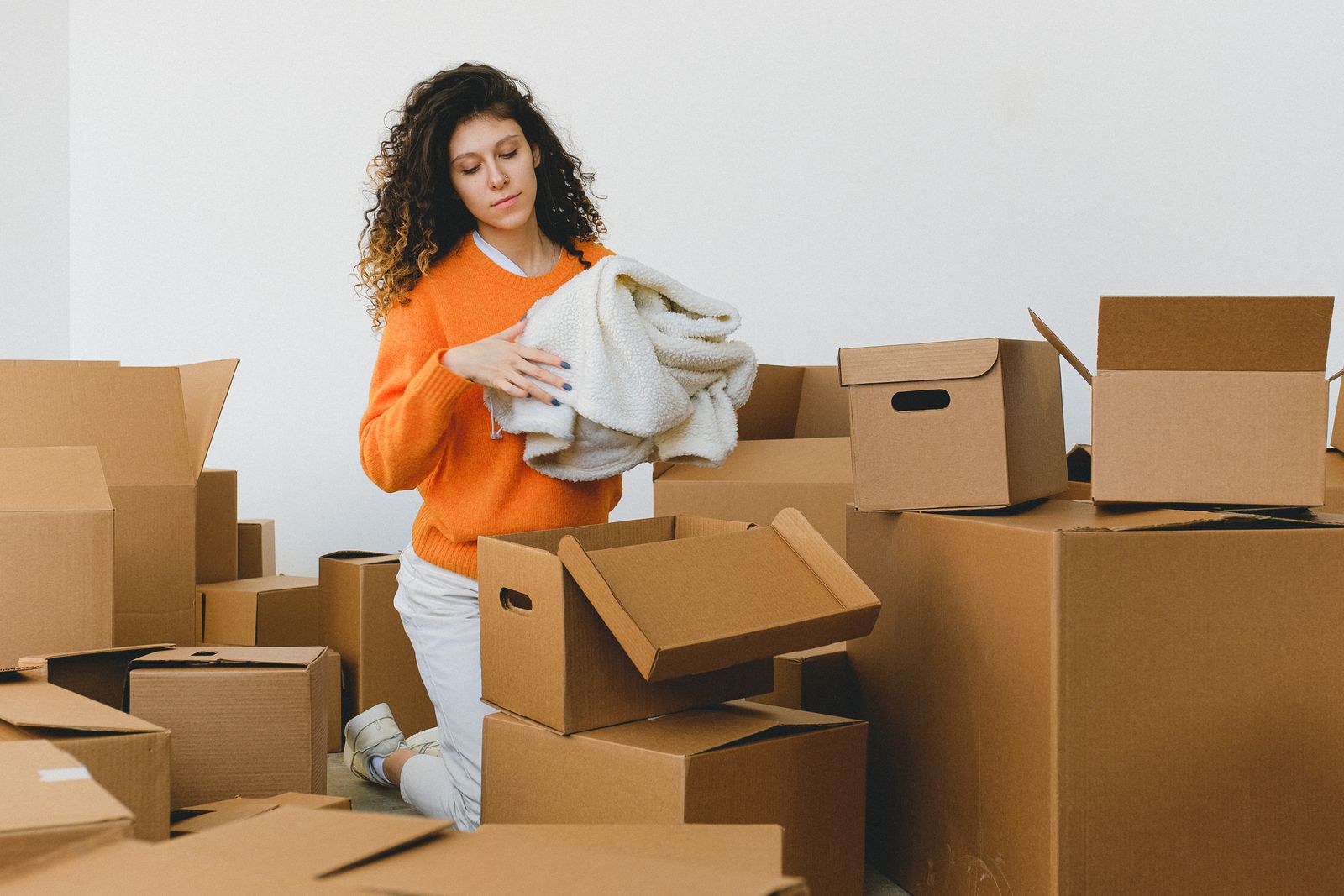 Woman carefully sorting and packing belongings into boxes during a downsize