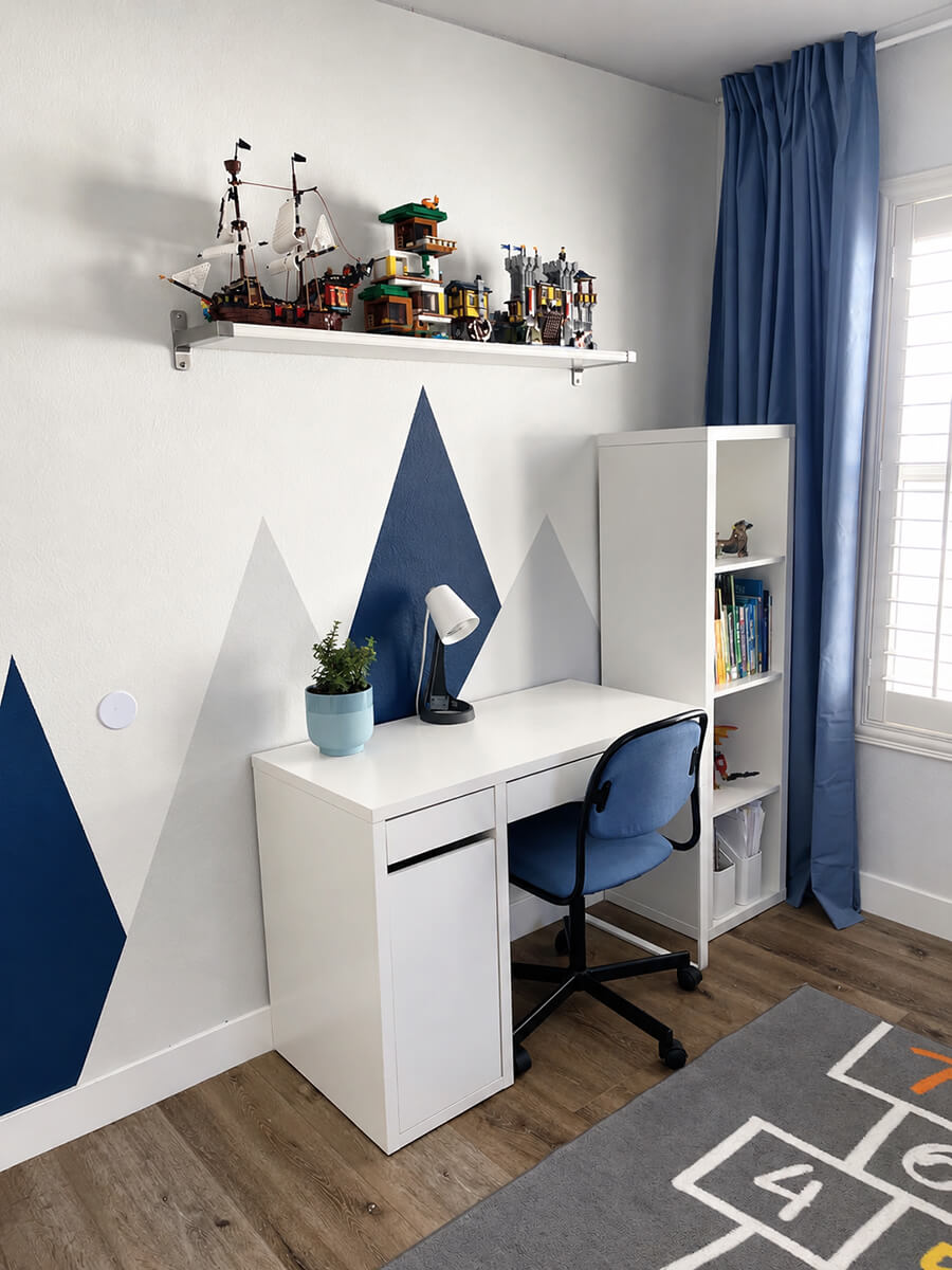Fully staged children's study room by Lifelystyle in Las Vegas — white desk with LEGO display shelf, navy blue curtains, geometric mountain mural, and bookcase that helps family buyers instantly picture their child's life in the home